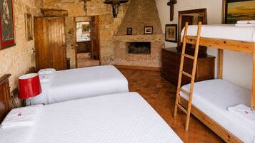 A rustic room with a stone fireplace, wooden bunk beds, and a ladder.