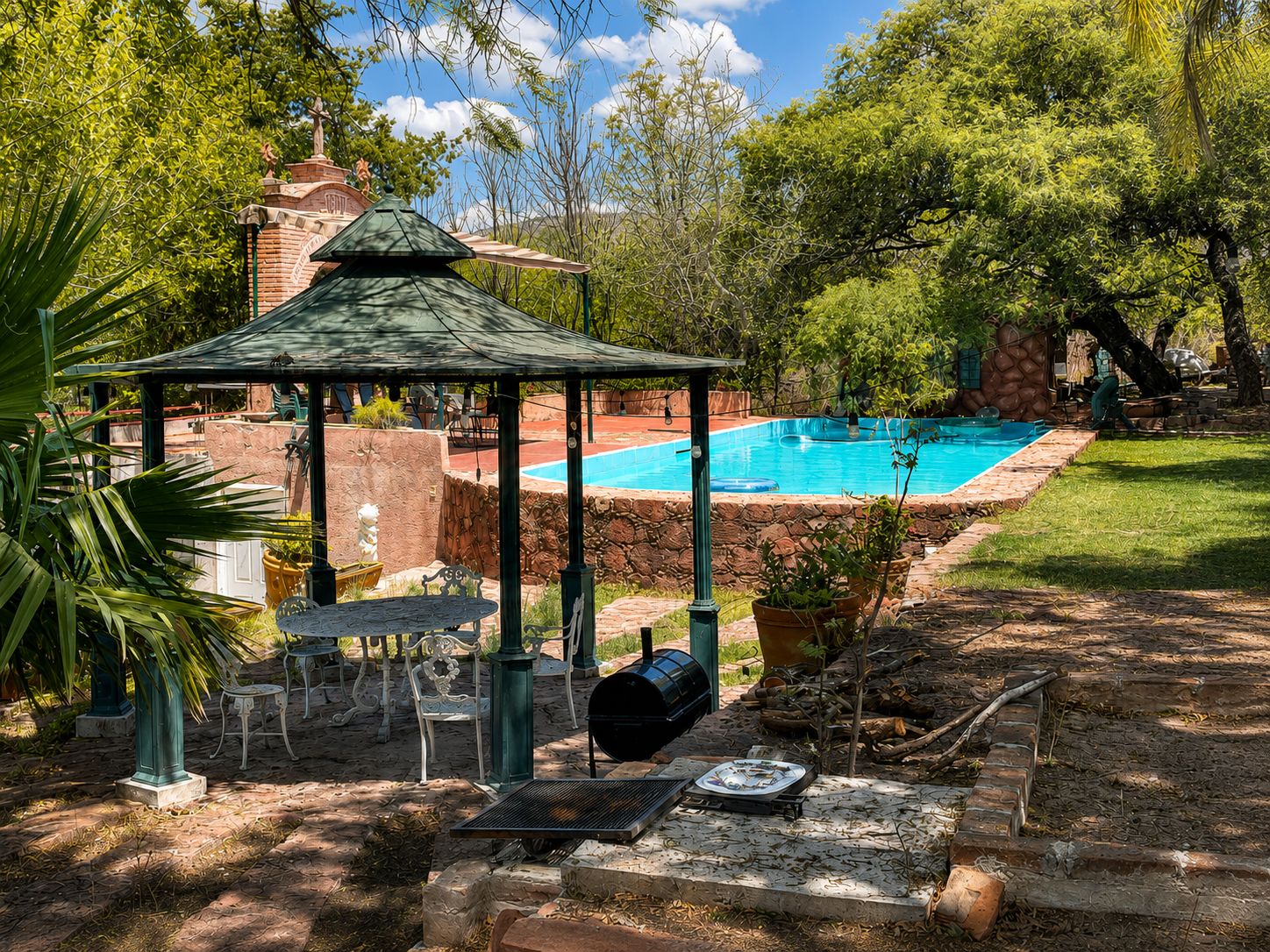 Un pabellón, mobiliario exterior, una parrilla y una piscina.