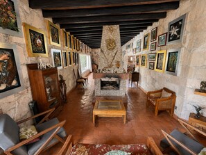 A cozy interior with a stone fireplace, wooden furniture, and artwork on the walls.