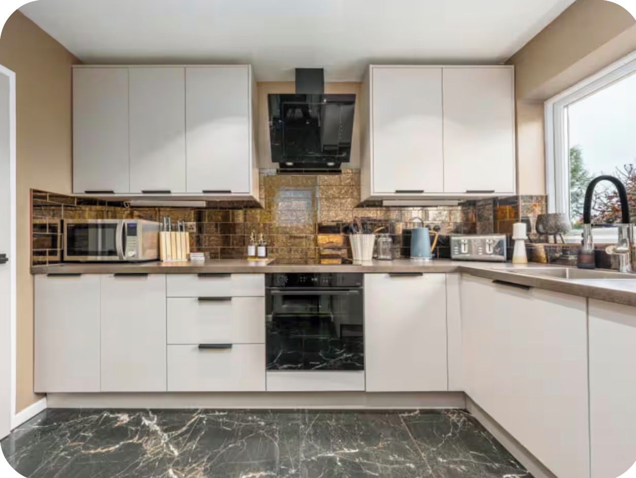 A modern kitchen with white cabinets, a microwave, an oven, and a sink.