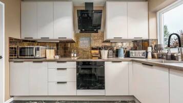 A modern kitchen with white cabinets, a microwave, an oven, and a sink.