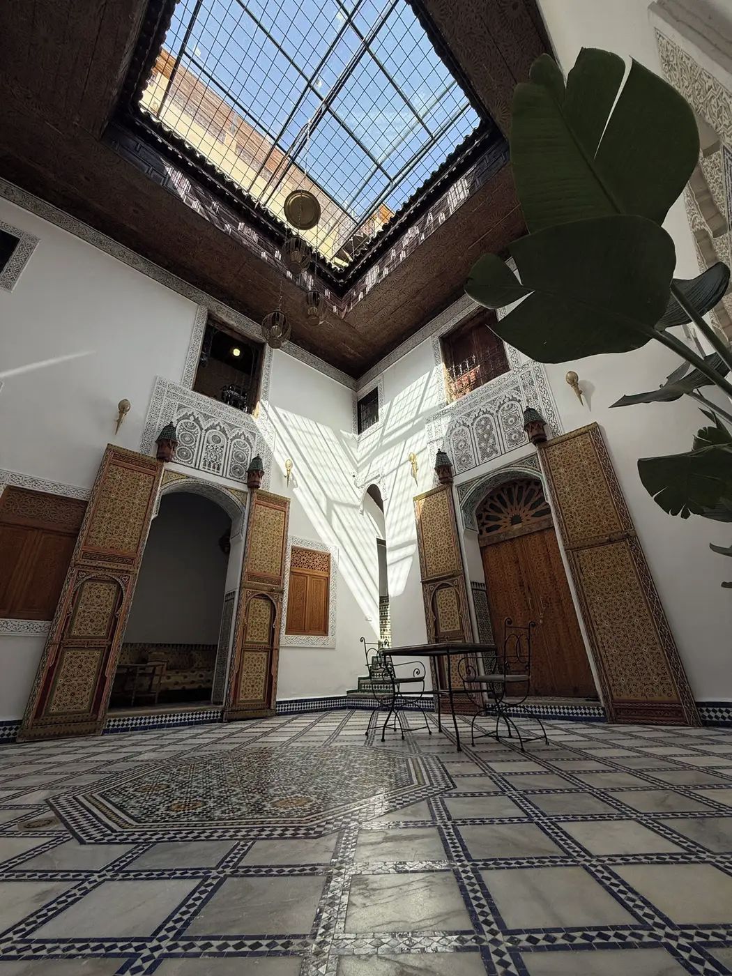 An interior with a high ceiling, patterned floor, and ornate wooden doors.