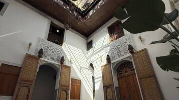 An interior with a high ceiling, patterned floor, and ornate wooden doors.