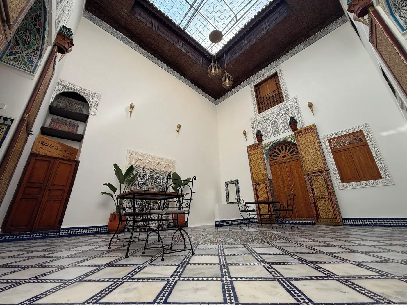 A room with a tiled floor, a central table, and a hanging light fixture.
