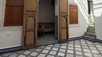 Un interior con puertas ornamentadas, un suelo a cuadros y una escalera.