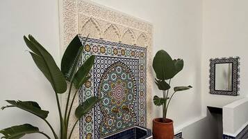 Una habitación con suelo de baldosas, una pared decorativa y plantas en macetas.