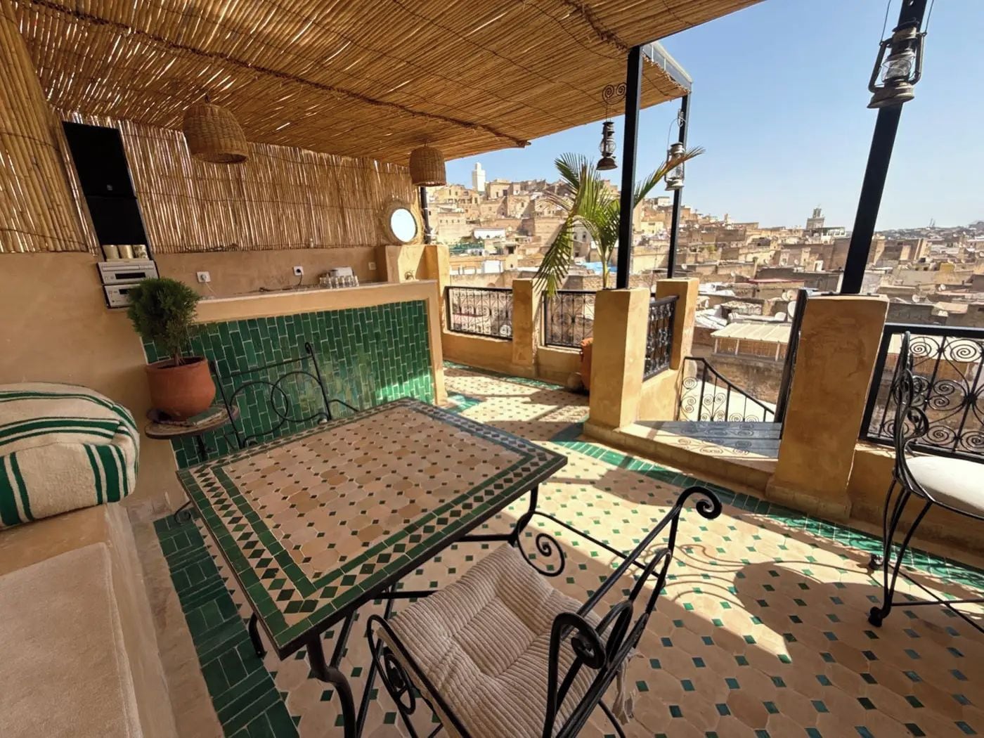 Una terraza en la azotea con una mesa, sillas, una planta en maceta y vistas de la ciudad.