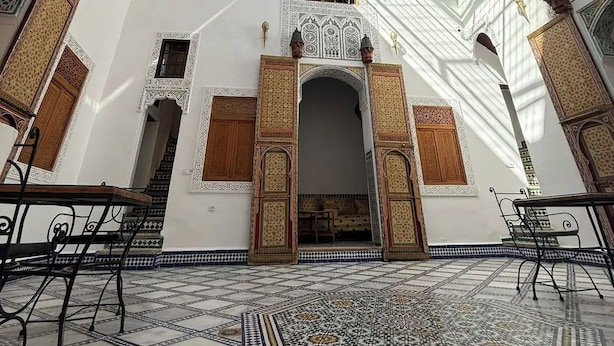 Un interior con suelo de baldosas, un arco central y paredes con diseños.