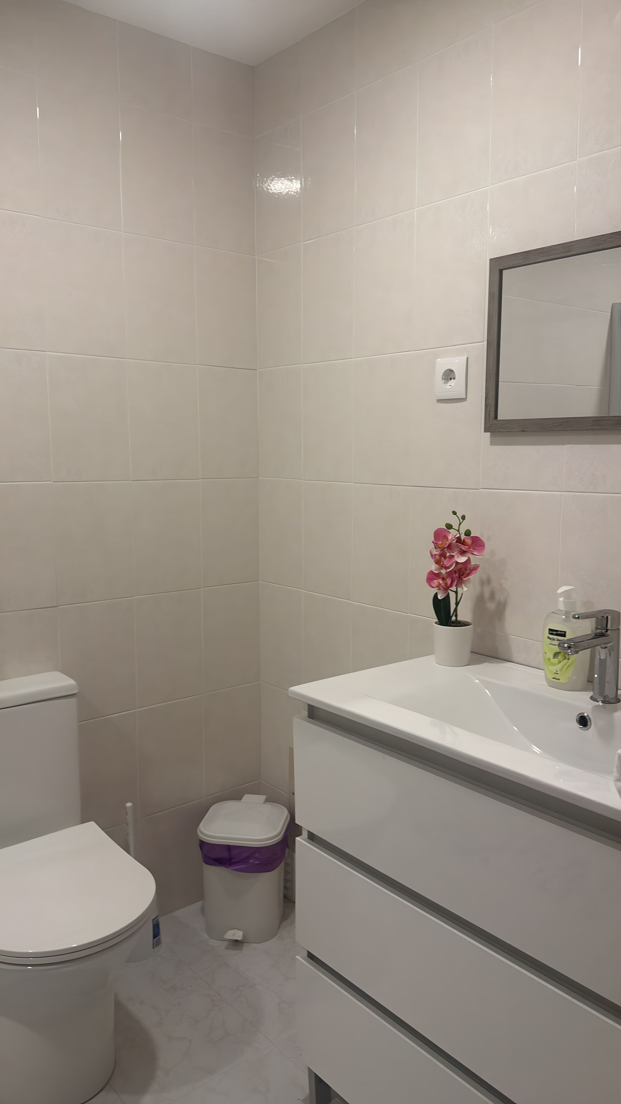 A bathroom with a toilet, sink, and trash bin.