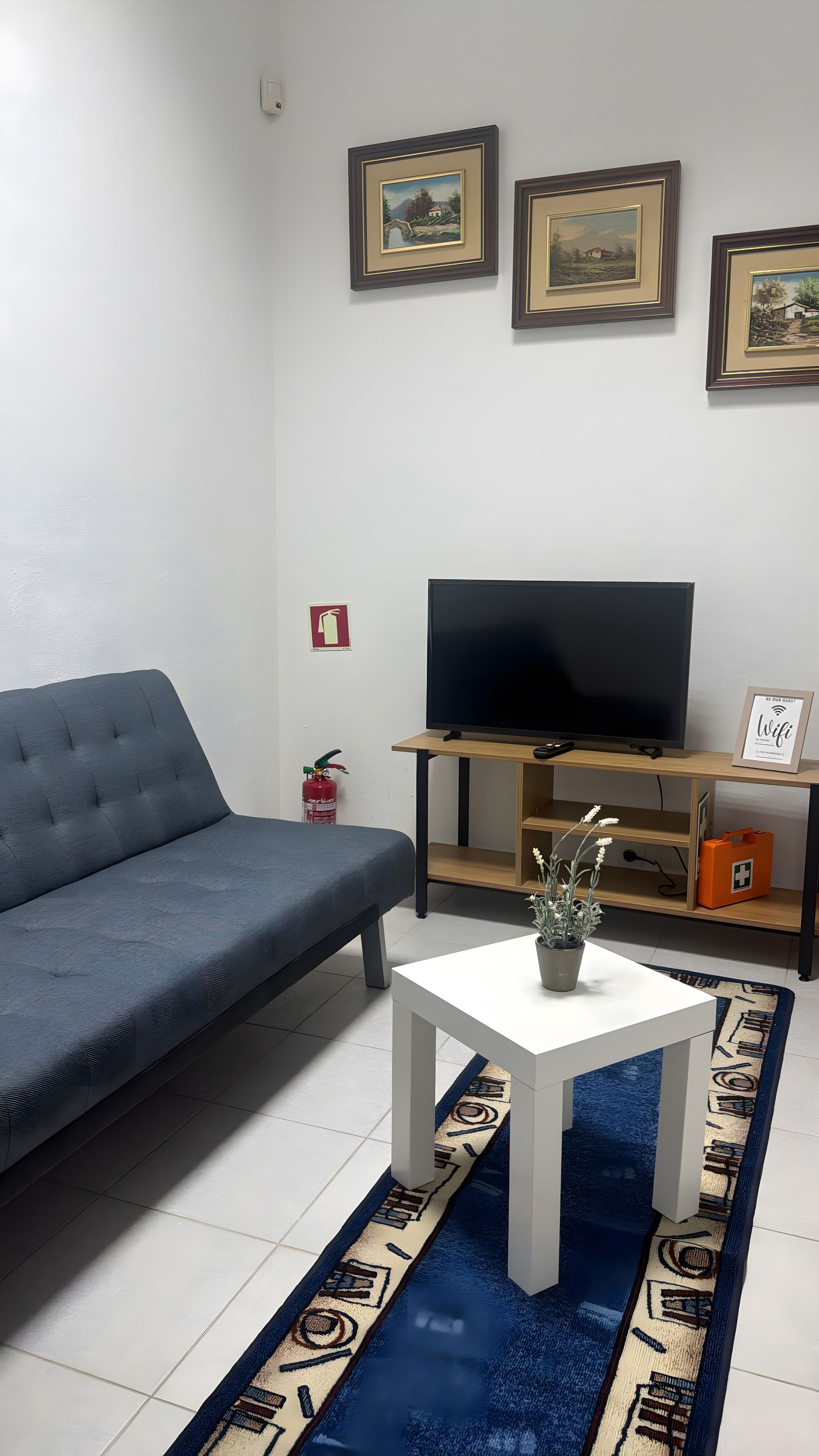 A living room with a sofa, a coffee table, a TV on a wooden stand, and framed pictures on the wall.
