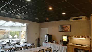 Een restaurant met tafels en stoelen, een toonbank met etalage en een plafond met inbouwverlichting.
