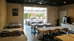 En restaurant med borde, stole, et stort vindue og et loft med indbygget belysning.