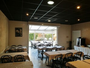 Un restaurant avec des tables et des chaises, une grande fenêtre et un plafond doté d’un éclairage encastré.