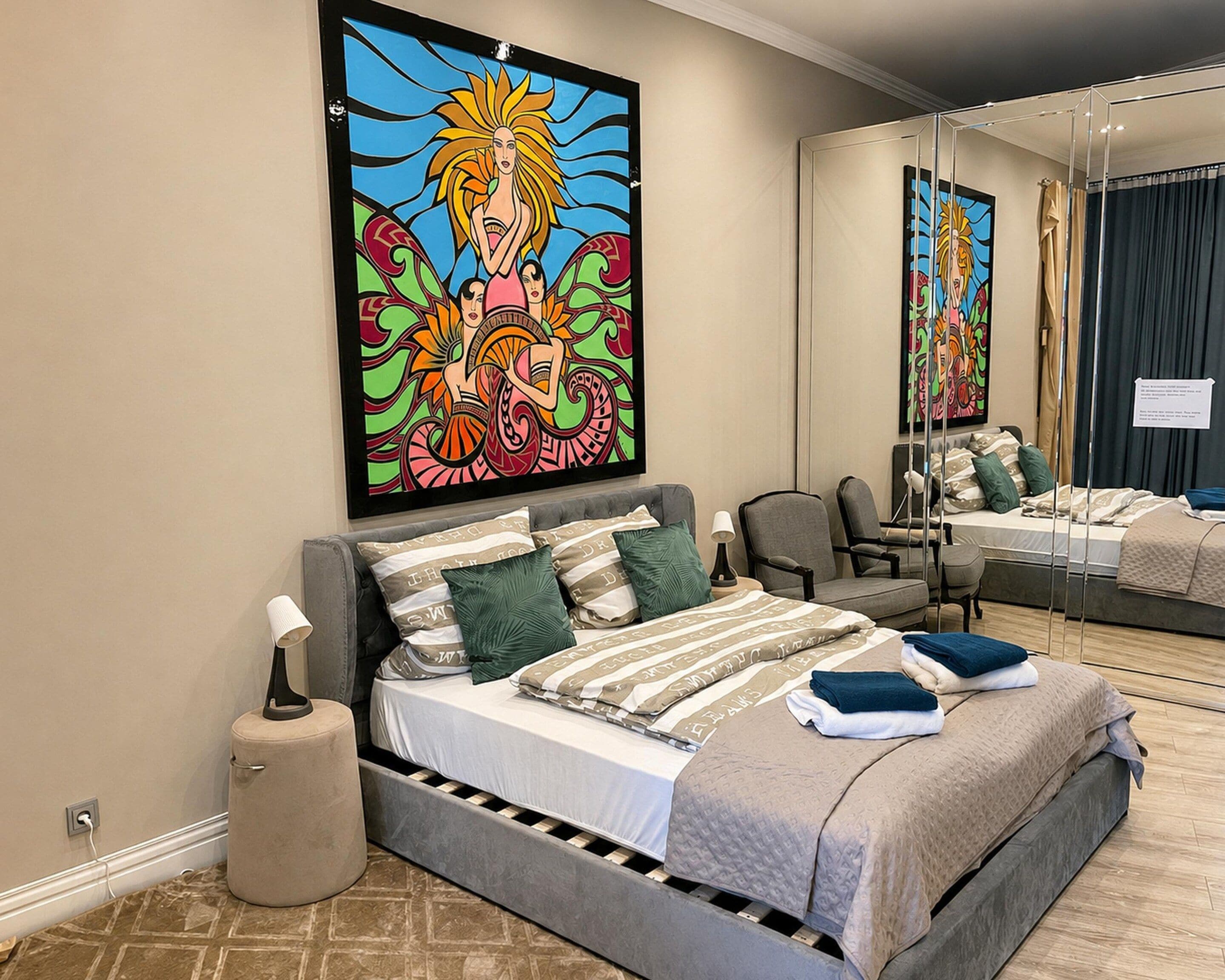 A modern bedroom with a large bed, a bedside table, a lamp, and a mirror.