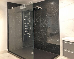Ein modernes Badezimmer mit einer gläsernen Dusche, Marmorwänden und einem minimalistischen Design.