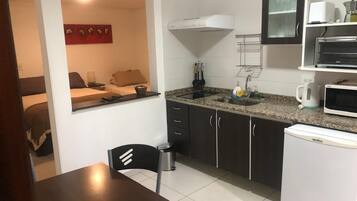 A compact kitchen with a dining area, a microwave, a sink, and a refrigerator.