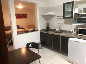 A compact kitchen with a dining area, a microwave, a sink, and a refrigerator.
