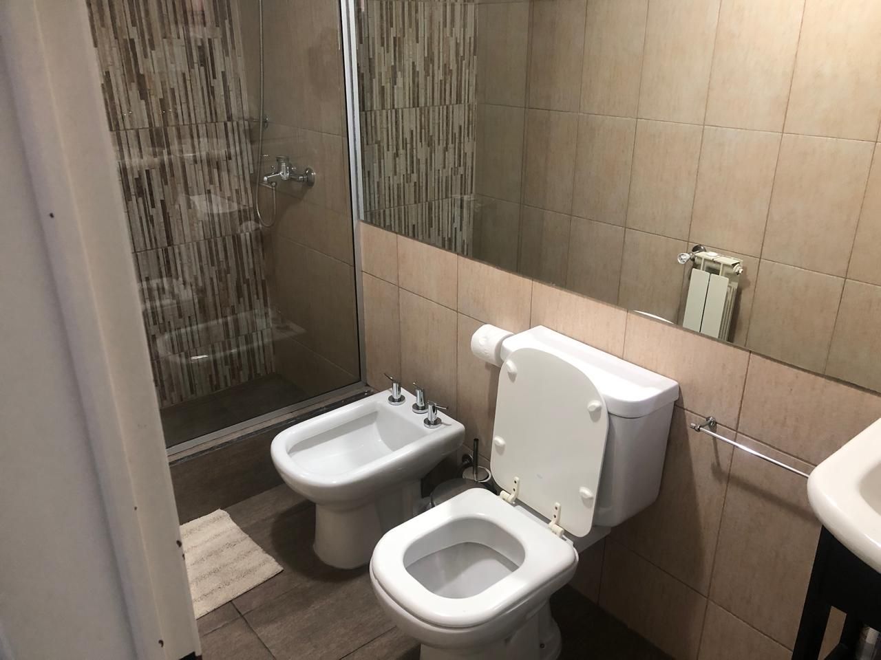 A bathroom with a bidet, toilet, and shower.