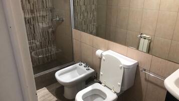 A bathroom with a bidet, toilet, and shower.