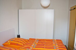 A room with a bed, a wardrobe, and a lamp. - The Nordwind vacation rental is located in the heart of Dornumersiel (Dornumersiel)