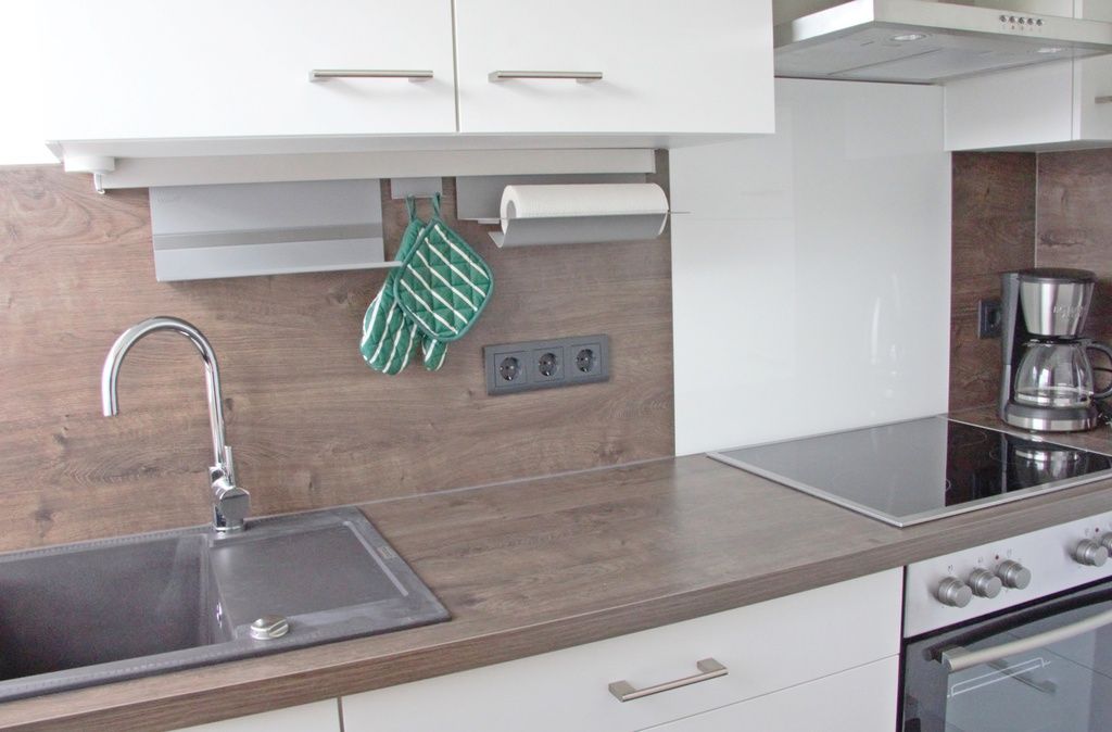 Una cocina moderna con un lavamanos de acero inoxidable, horno empotrado y cafetera.