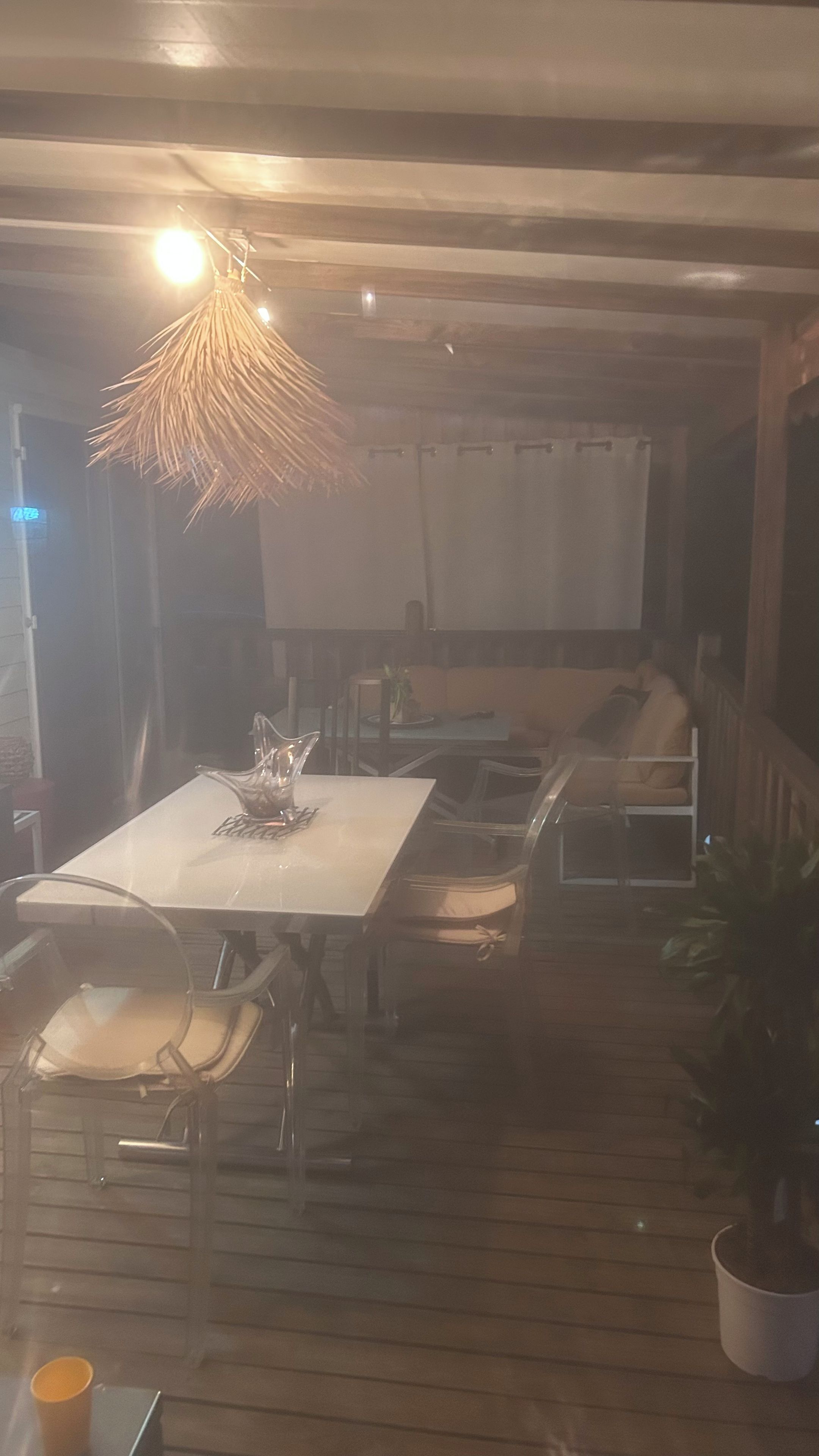 Uma área de refeições com mesa e cadeiras, luminária pendente e planta em vaso.