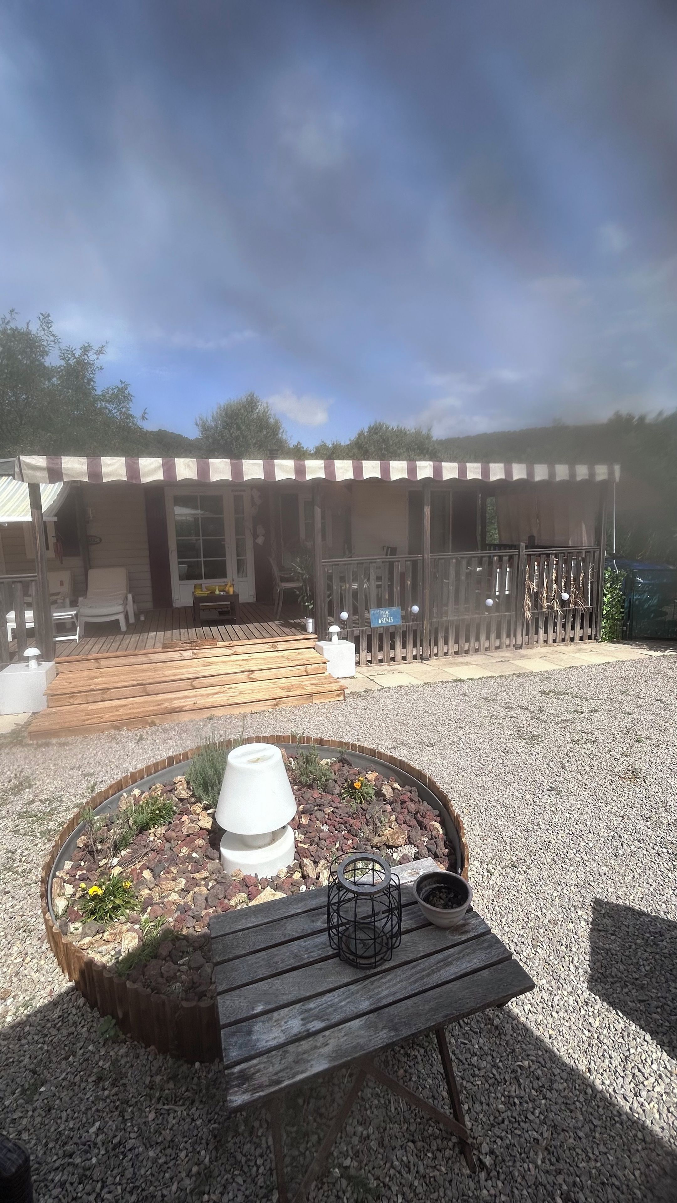 A covered outdoor seating area with a table and a planter in the foreground.