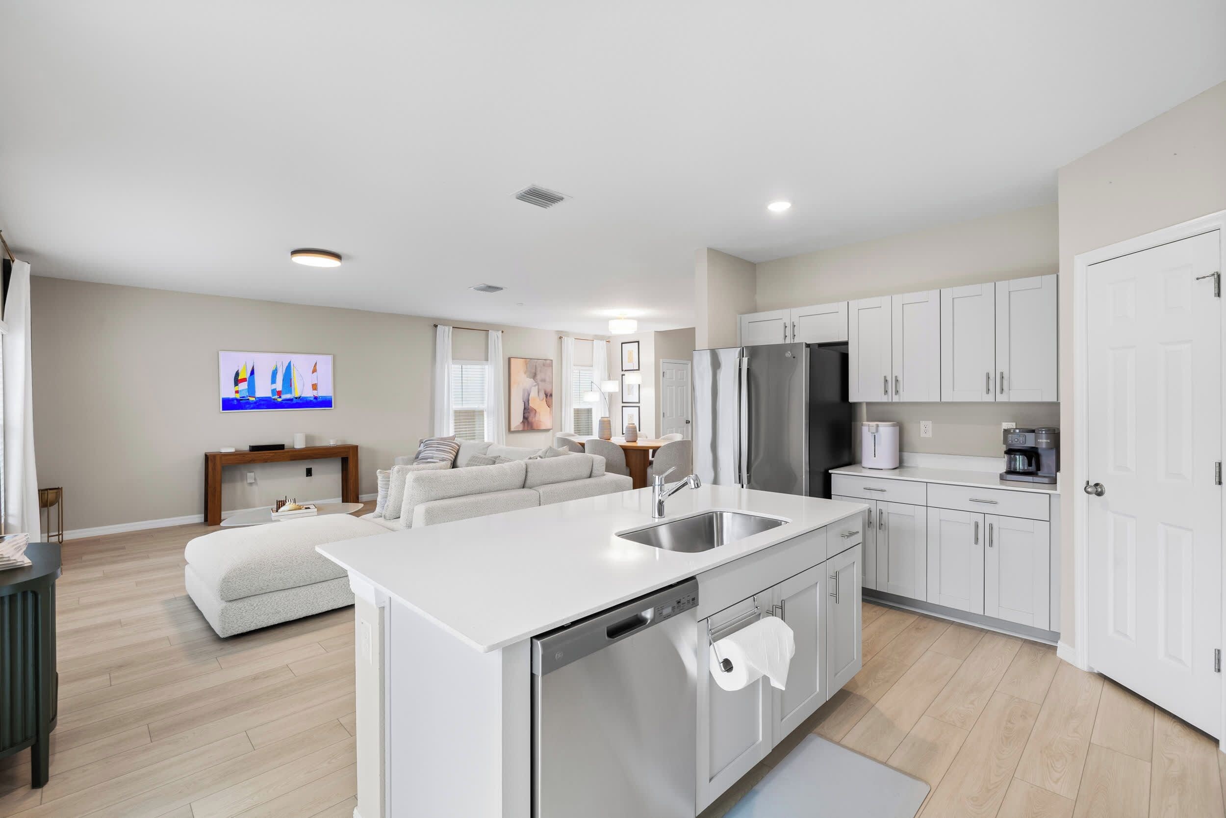 A modern kitchen with white cabinetry, a stainless steel refrigerator, and a built-in dishwasher.