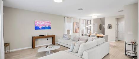 A modern living room with a sofa, coffee table, and artwork on the wall.