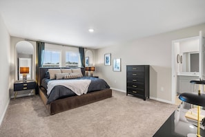 Quarto com cama, mesas de cabeceira, penteadeira e espelho.