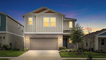 A two-story residential house with a garage, a driveway, and a well-maintained lawn.