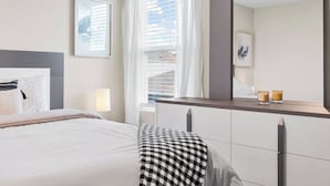 Un dormitorio moderno con cama, lámpara de noche y un espejo grande.