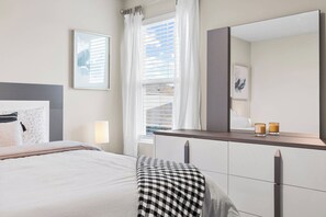 Quarto moderno com cama, luminária de cabeceira e um espelho grande.