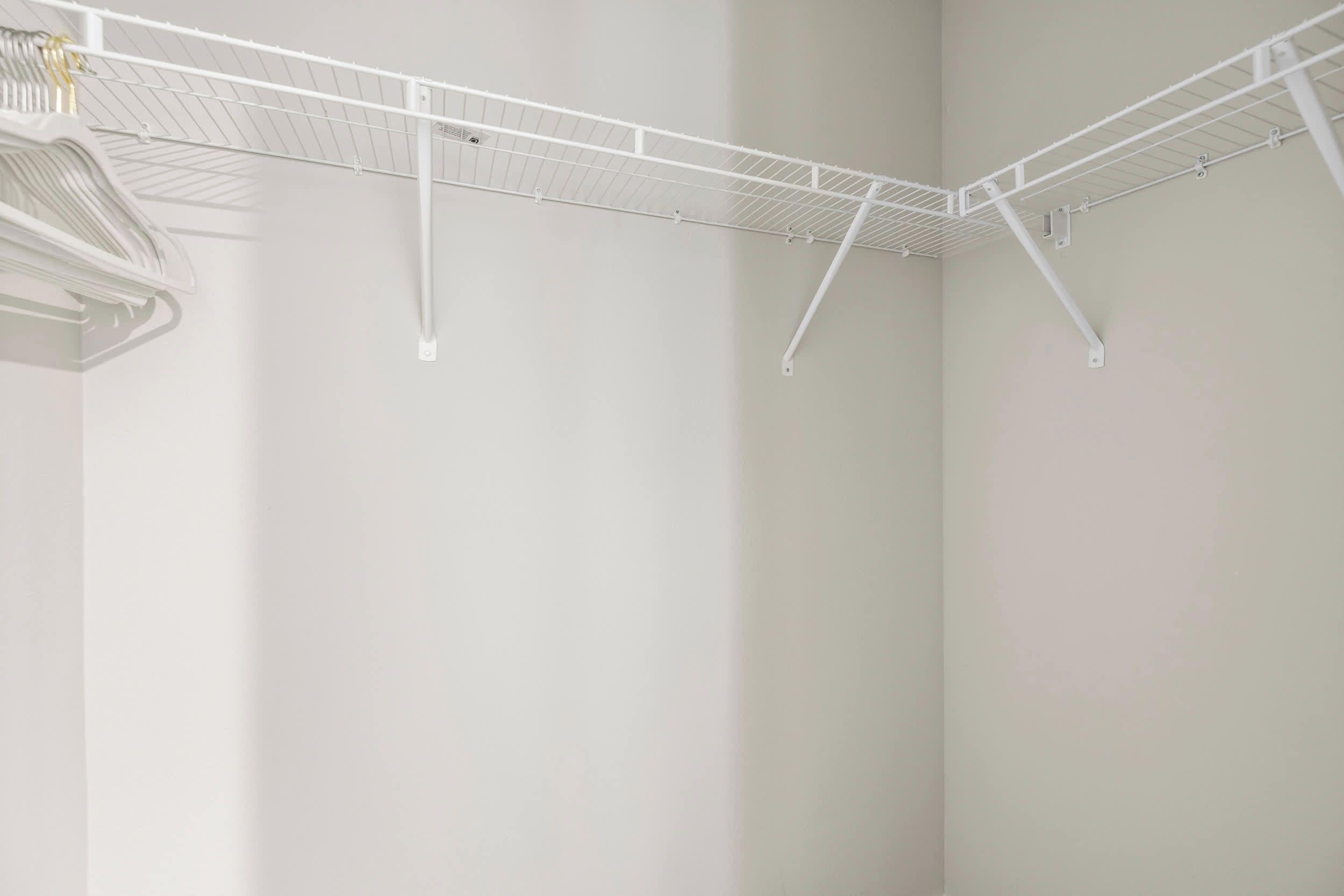 A white metal drying rack in a corner of a room with plain walls.