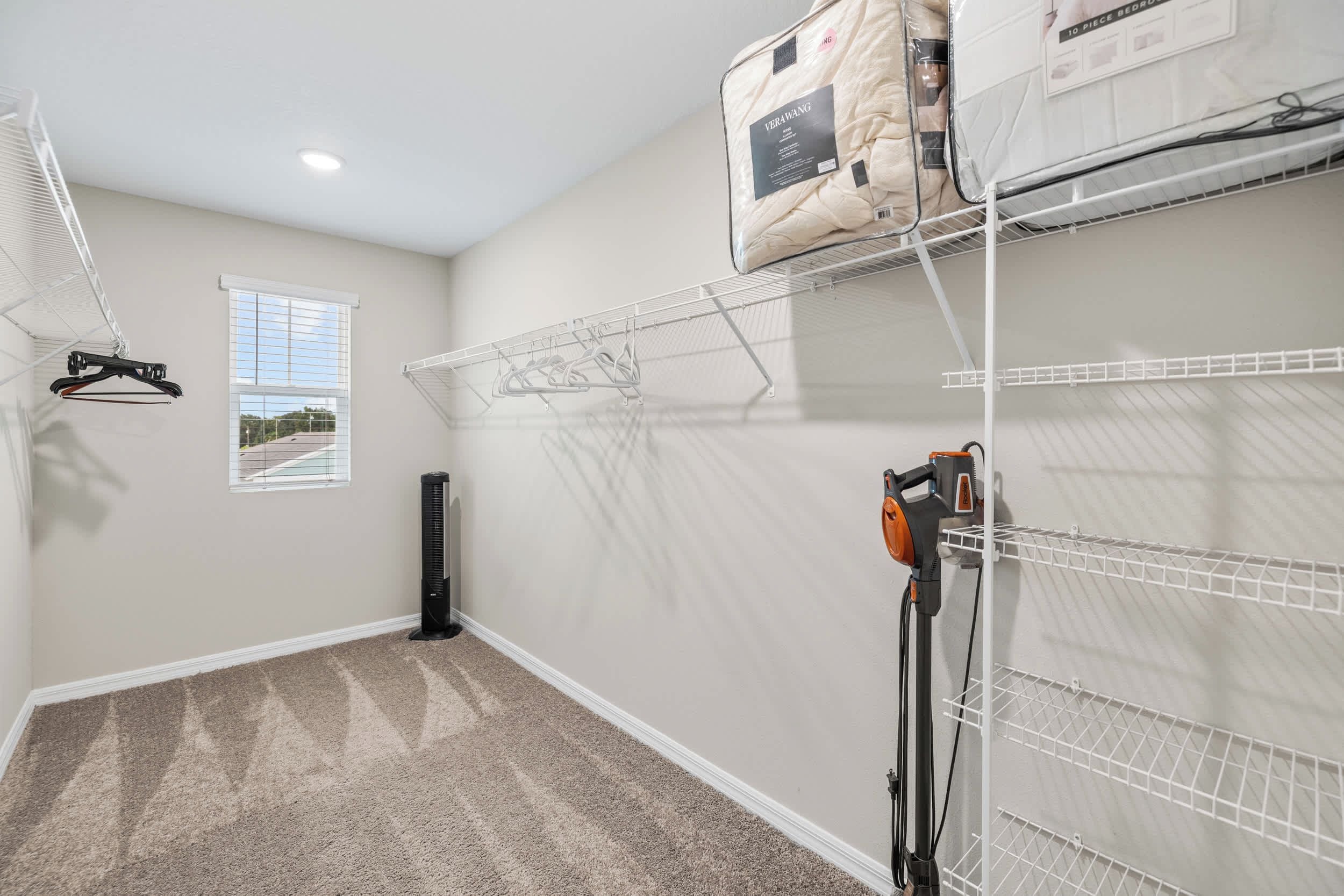 A laundry room with a drying rack, a vacuum cleaner, and storage shelves.