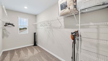 A laundry room with a drying rack, a vacuum cleaner, and storage shelves.