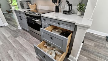 Una cocina moderna con armarios grises, horno empotrado y encimera con cafetera y utensilios.