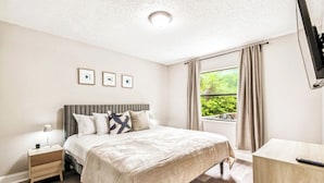 A hotel room with a bed, bedside table, and a TV. - Charming Home Near Macdill AFB Hot Tub Fire Pit (Tampa)