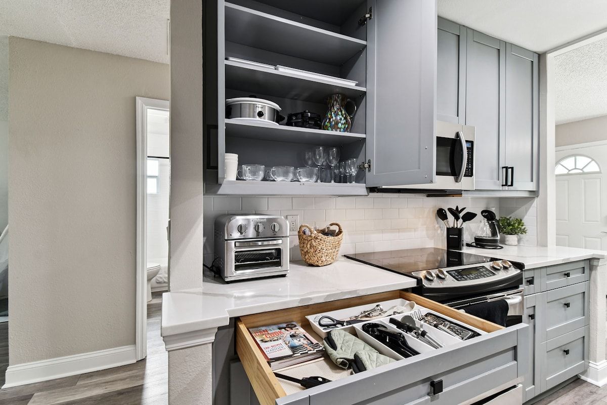 A kitchen with a built-in oven, microwave, and a drawer with kitchen utensils.