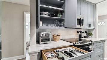 A kitchen with a built-in oven, microwave, and a drawer with kitchen utensils.