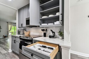 A modern kitchen with grey cabinets, a built-in oven, and a countertop with a coffee maker and utensils.