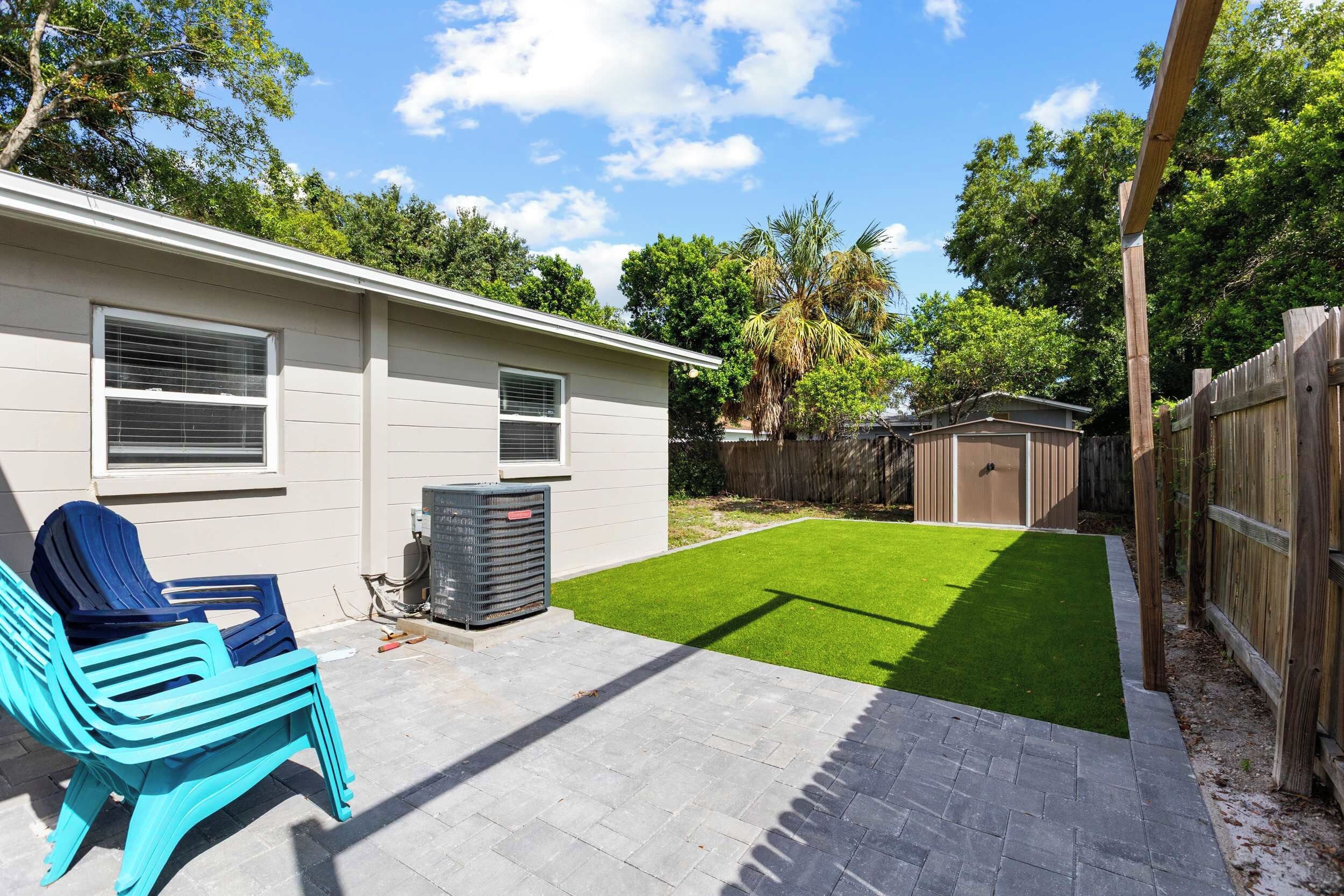 A residential backyard with a patio, a lawn, and a wooden fence.