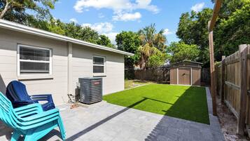 A residential backyard with a patio, a lawn, and a wooden fence.