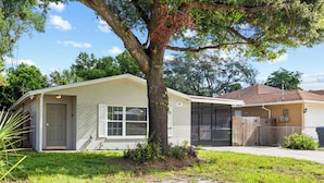 A single-story house with a front porch, a garage, and a tree in the yard. - NEW - 3BD Cozy Downtown Retreat! (Tampa)
