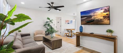 A modern living room with a sofa, coffee table, and a TV mounted on the wall.