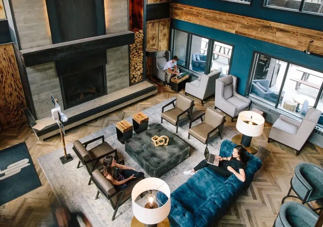 A spacious living room with a fireplace, modern furniture, and large windows offering a view of the outside.