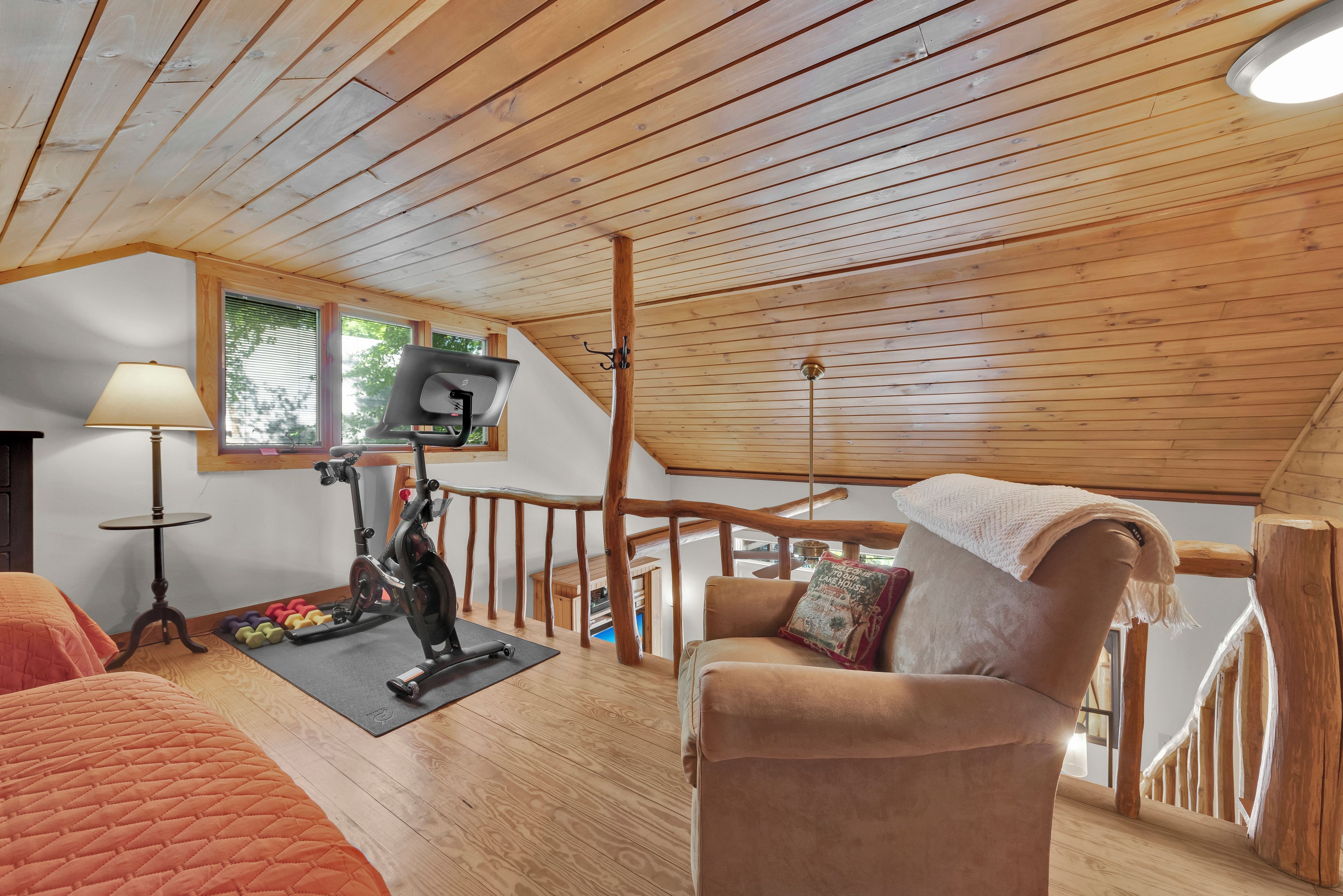 A wooden interior with a ceiling fan, a treadmill, and a cushioned chair.