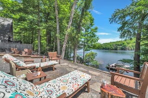 An outdoor seating area with lounge chairs and tables, overlooking a lake with boats. - The Overlook, Lake Wallenpaupack, Boat Slip+Kayak, Private Dock (Greentown)