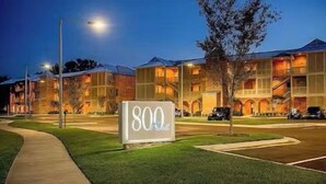 Um hotel com vários andares, placa indicando 800 quartos, gramado bem cuidado e céu noturno limpo.
