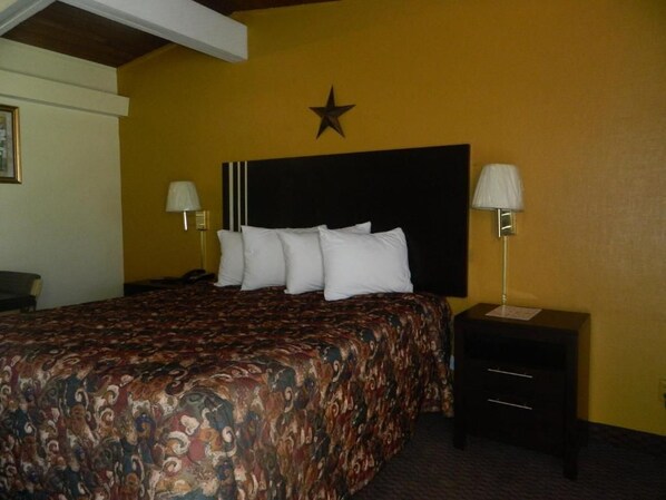 A hotel room with a bed, two bedside tables, a star decoration on the wall, and a lamp on each table.